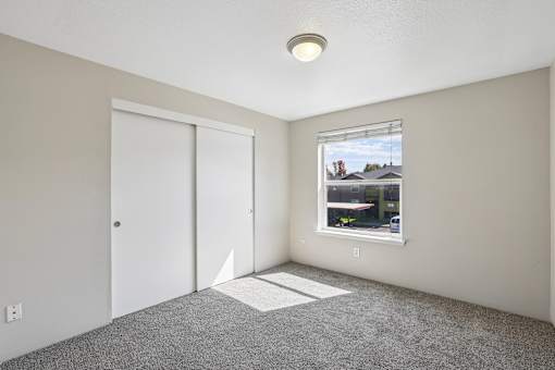 A room with a window, carpeted floor, and a ceiling light.