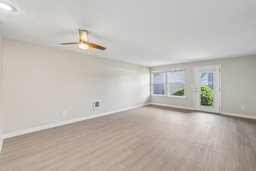 A room with a ceiling fan and sliding glass doors.