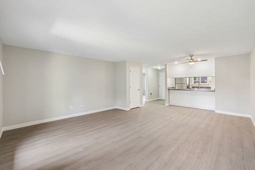 A spacious room with light wood flooring and white walls.