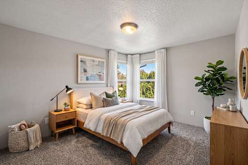 A bedroom with a large bed and a window overlooking a green landscape.