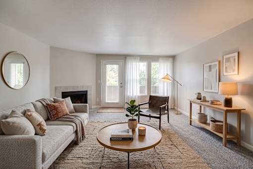 A living room with a grey couch, a coffee table, a fireplace, and a chair.