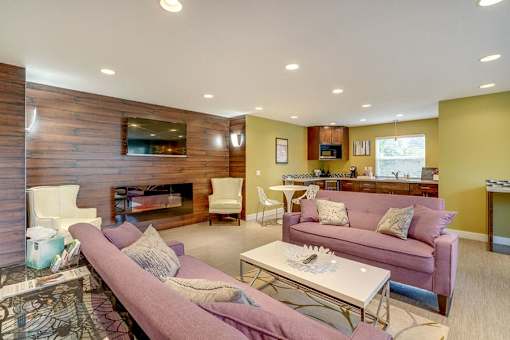 A living room with a purple couch and a fireplace.