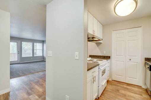 A kitchen with white cabinets and a wooden floor.