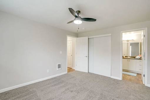 A room with a ceiling fan and carpeted floor.