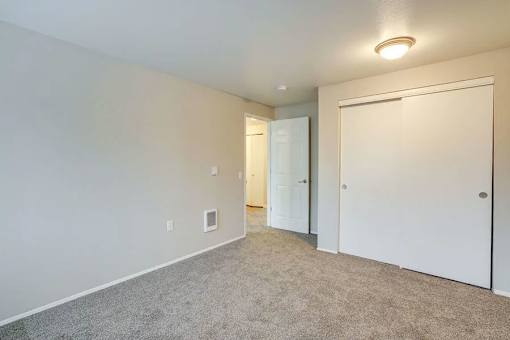 A room with a carpeted floor and two white doors.