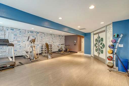 A gym with a blue wall and a variety of exercise equipment.