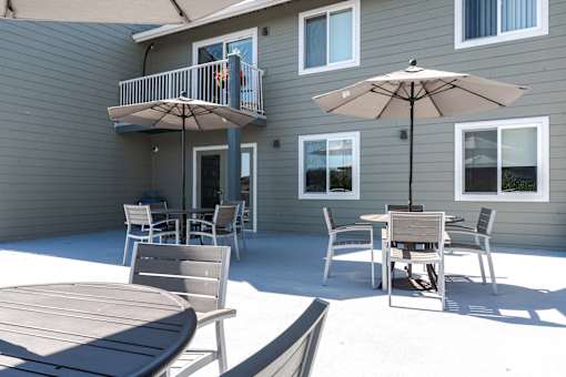 A patio with a table and chairs and an umbrella.