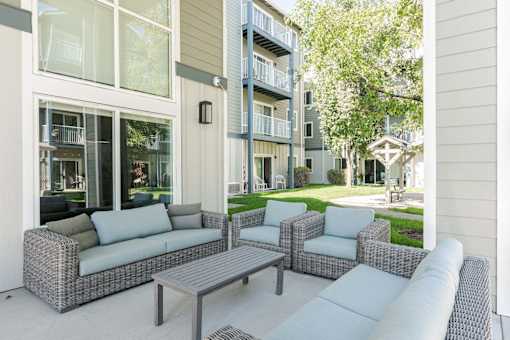 A patio with a grey sofa, two chairs and a table.