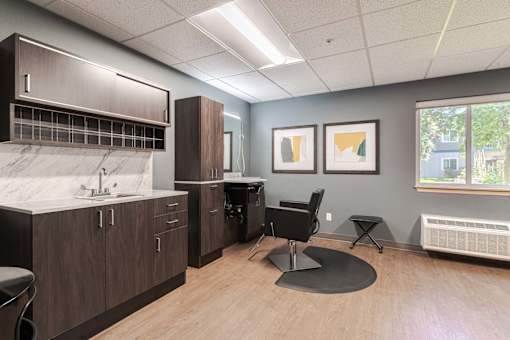 A room with a sink, a chair, and a window.