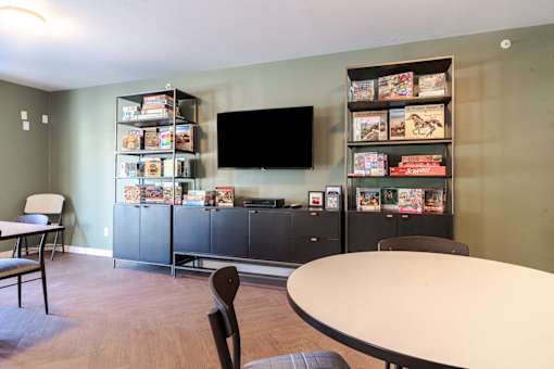 A room with a table, chairs, and a bookshelf filled with books.