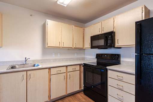 A kitchen with black appliances and wooden cabinets.