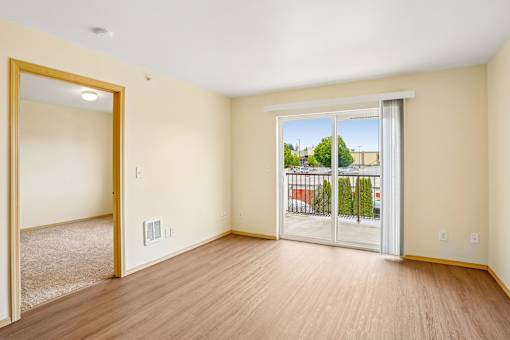 A room with a view of a fence and trees through a sliding glass door at Vintage at Burien, Burien, Washington