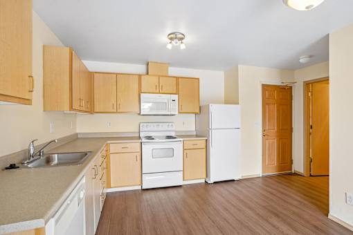 A kitchen with wooden cabinets and white appliances at Vintage at Burien, Burien.
