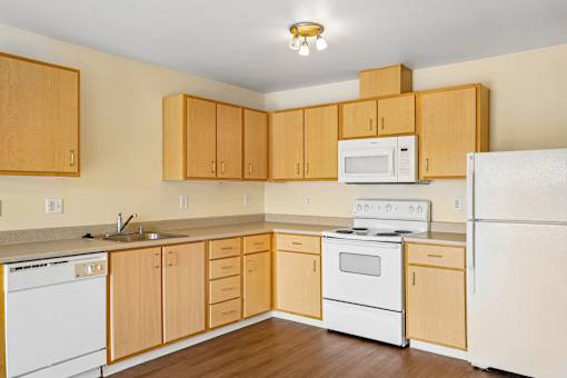 A kitchen with wooden cabinets and white appliances at Vintage at Burien, Washington,98168