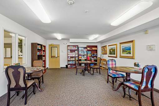 A room with a carpeted floor and a collection of chairs and tables at Vintage at Burien, Burien