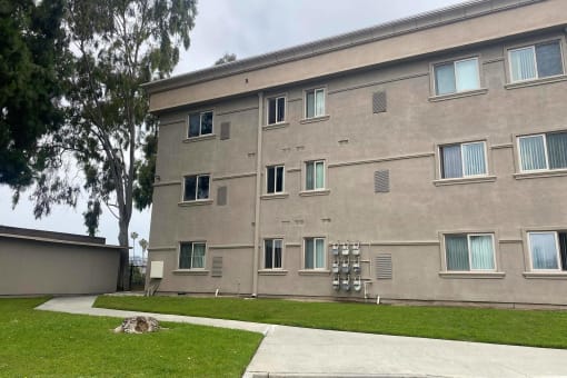 the side of a building with grass and a sidewalk