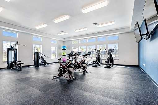A gym with a variety of exercise equipment including treadmills, stationary bikes, and elliptical machines at View by Vintage Apartments, Washington, 98391