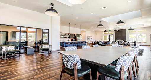 A large dining room with a long table and chairs at View by Vintage Apartments, Bonney Lake, WA 98391