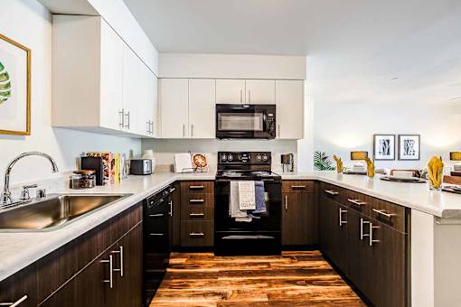 A modern kitchen with dark wood cabinets and a white countertop at View by Vintage Apartments, Bonney Lake, WA
