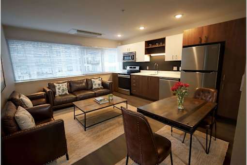 A modern kitchen and living room with brown leather furniture.