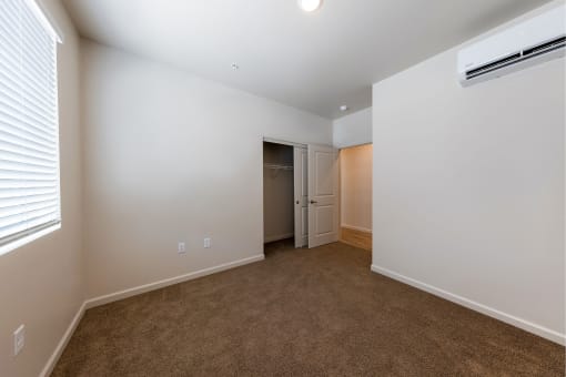 a bedroom with white walls and carpet and a door to a closet at Springview by Vintage, Reno, NV, 89512