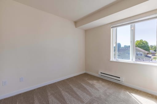 an empty bedroom with a large window and carpeting
