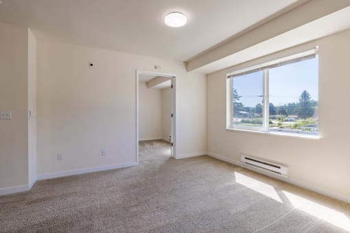 an empty living room with a large window and carpet