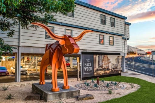 large orange sculpture of a cow in front of a building at THE EASTWOOD, AUSTIN, TX 78705