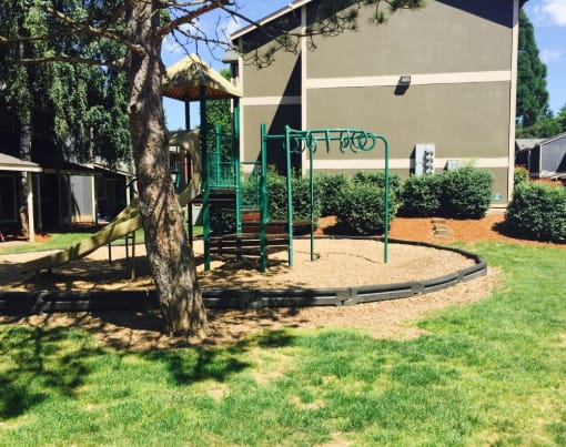 a swing set in front of apartment building with a tree at Fort Vancouver Terrace, Vancouver, 98661