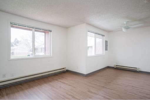an empty room with wood floors and two windows at Fort Vancouver Terrace, Vancouver, WA
