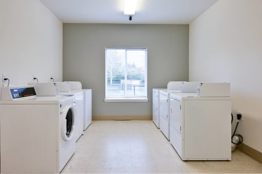 an empty laundry room with dryers and washing machines at Quail Run Apartments, Vancouver