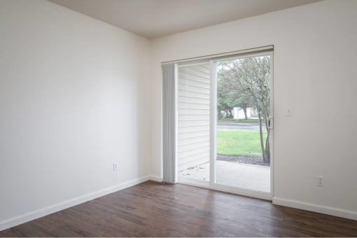 an empty living room with a sliding glass door to a yard at Quail Run Apartments, Vancouver, Washington