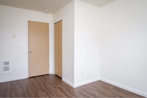 an empty room with white walls and wooden floors and two doors at Quail Run Apartments, Vancouver, Washington