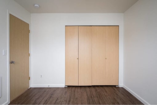 an empty room with white walls and wooden floors at Quail Run Apartments, Washington 98684