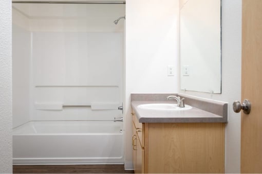 a bathroom with a sink and a shower and a mirror at Quail Run Apartments, WA