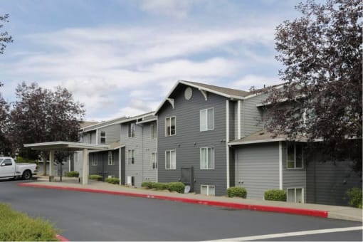 an apartment building with gray siding and a red curb at Troutdale Terrace, Troutdale, OR