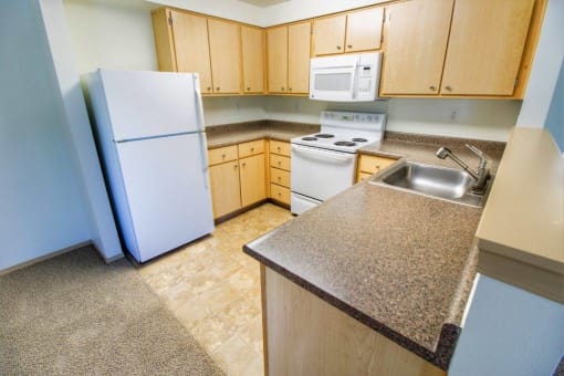 a kitchen with a white refrigerator and a sink at Troutdale Terrace, Troutdale, OR 97060