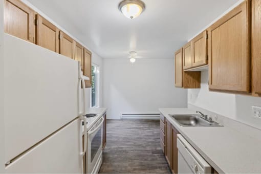 a kitchen with white cabinets and a sink and a refrigerator at Whisperwood, Seattle, WA