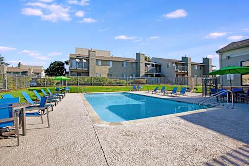 A swimming pool surrounded by chairs and a building in the background at The Henley Apartments, Suisun City, CA