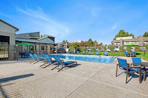 A pool area with sun loungers and a building in the background at The Henley Apartments, Suisun City, CA
