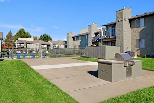 A concrete structure sits in the middle of a grassy area in front of apartment buildings at The Henley Apartments, Suisun City, CA