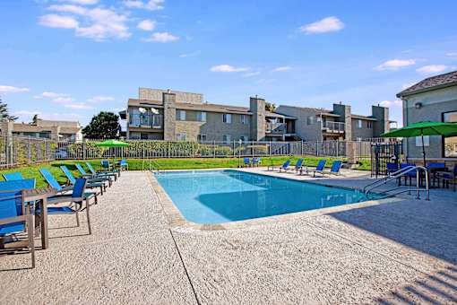 A pool surrounded by chairs and a building in the background at The Henley Apartments, Suisun City, CA, 94585
