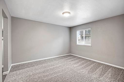 A room with a carpeted floor and a window with blinds at The Henley Apartments, California, 94585
