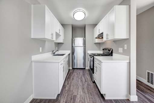 A kitchen with white cabinets and a stainless steel refrigerator at The Henley Apartments, Suisun City, CA