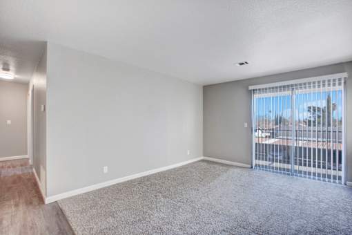 A room with a carpeted floor and a sliding glass door at The Henley Apartments, California, 94585