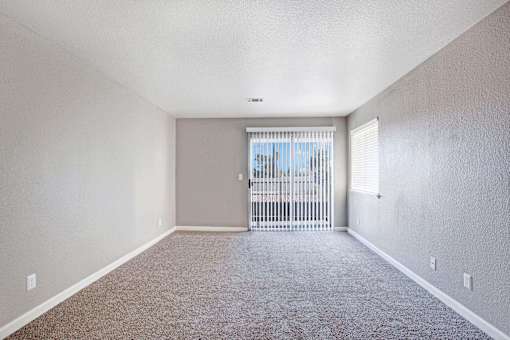 A room with a carpeted floor and a sliding glass door at The Henley Apartments, Suisun City, California