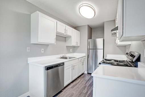 A modern kitchen with white cabinets and stainless steel appliances at The Henley Apartments, Suisun City, CA, 94585