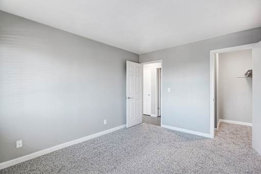 A room with a carpeted floor and a white door at The Henley Apartments, Suisun City, CA