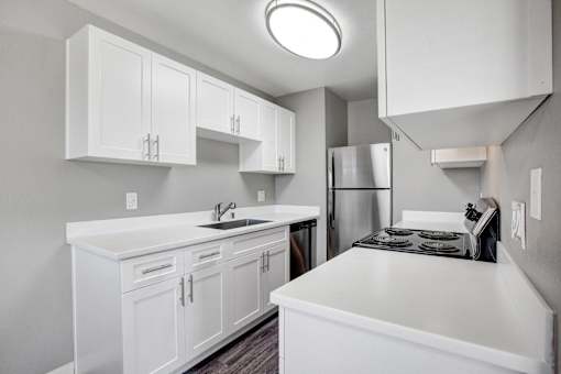 A kitchen with white cabinets and a stainless steel refrigerator at The Henley Apartments, Suisun City, CA