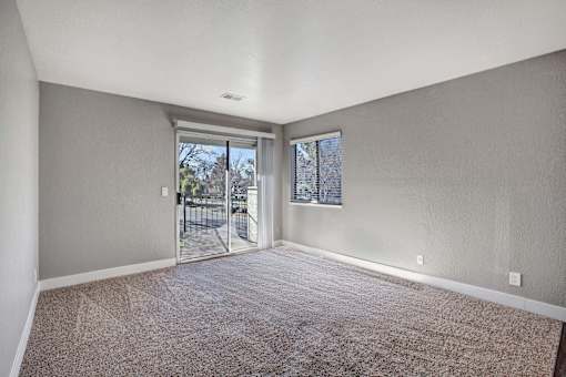 A room with a carpeted floor and a sliding glass door leading outside at The Henley Apartments, California
